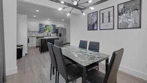 A modern kitchen with white cabinets, a black countertop, and a ceiling light fixture.