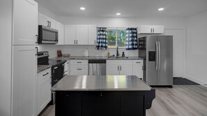 A modern kitchen with white cabinets, stainless steel appliances, and a central island.