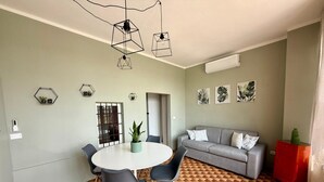 A modern living room with a round dining table, grey sofa, and patterned floor. - ThreeZeroThree House • With Private Garden (Colombaro)