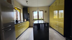 Ett modernt kök med en köksö i mitten, vitvaror i rostfritt stål och gula skåp.