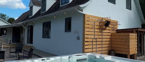 Une maison moderne avec une piscine, une terrasse en bois et un ciel d’un bleu éclatant.