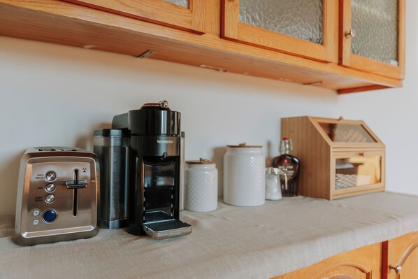 A kitchenette with a toaster, a coffee maker, and storage jars on a countertop.