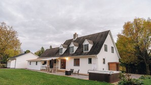 Una casa de dos pisos con un patio, mobiliario exterior y un jacuzzi.