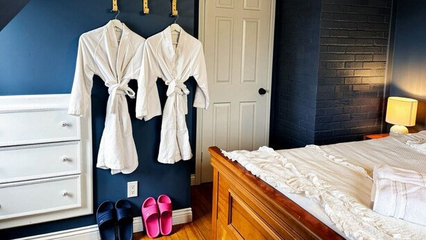A bedroom with a bed, a dresser, a door, and two pairs of slippers.