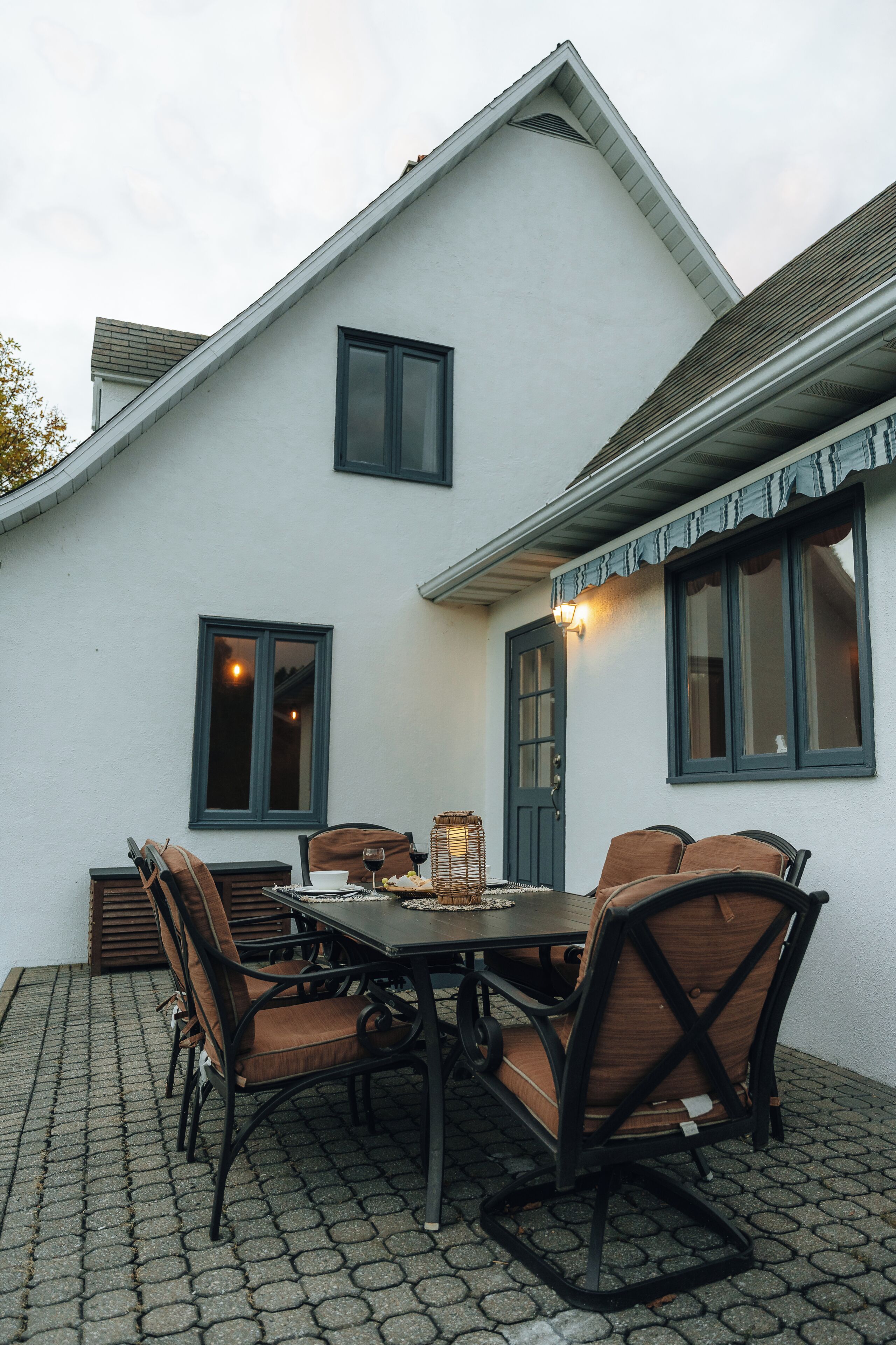 Un patio al aire libre con una mesa, sillas, una cesta y una ventana con una lámpara.