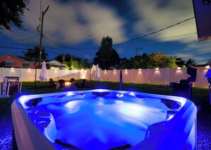 A hot tub with a blue light, surrounded by a white fence, chairs, and a fire pit. - Delray Beach 3BR: Walk to Atlantic Ave - Hot Tub & Game Room (Delray Beach)