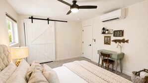 Een slaapkamer met een bed, een bureau, een stoel, een plafondventilator en een airconditioning.