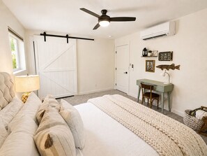Ein Schlafzimmer mit Bett, Schreibtisch, Stuhl, Deckenventilator und Klimaanlage.