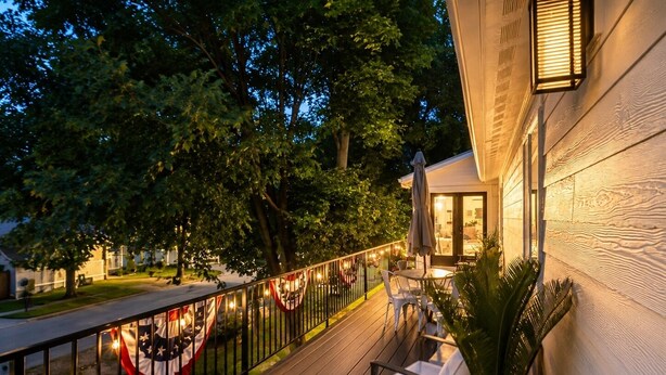 Een terras met buitenmeubilair, een hekwerk en uitzicht op een huis.