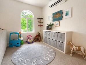 Ein Kinderzimmer mit einem großen Fenster, Stauraumschränken und einem Teppich mit Zahlen.