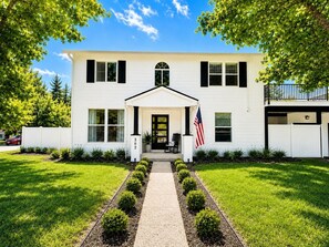 Ein zweigeschossiges weißes Haus mit Veranda, Briefkasten und einer amerikanischen Flagge.