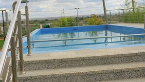 Une piscine avec des marches menant à l’intérieur, entourée d’une rambarde en métal.