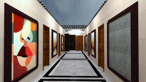 En hall med inramade konstverk på väggarna, en mönstrad matta och ett tak med en unik design.