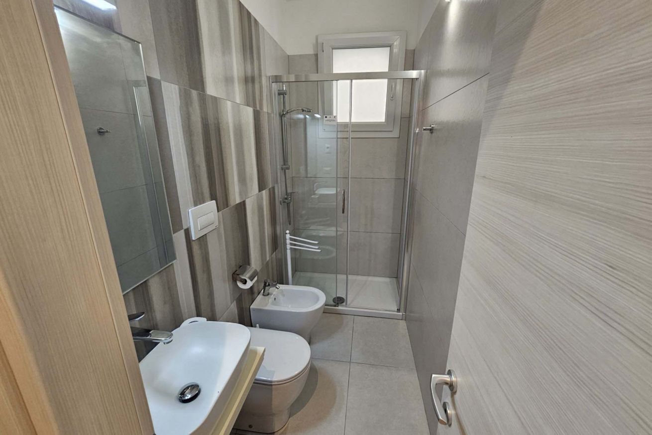 Een badkamer met douche, toilet en wastafel.