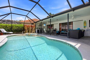 Ein Swimmingpool mit Glasveranda, Sitzgelegenheiten im Freien und Blick auf die Umgebung.