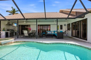 Ein überdachter Außenbereich mit Swimmingpool, Terrassenmöbeln und Grill.