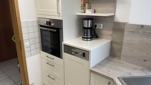 Una cucina compatta con lavastoviglie Bosch, una macchina per il caffè e un forno integrato.