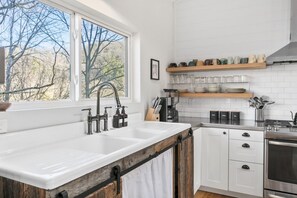 Eine moderne Küche mit großem Fenster, weißen Schränken und einer Wand mit Holzverkleidung.