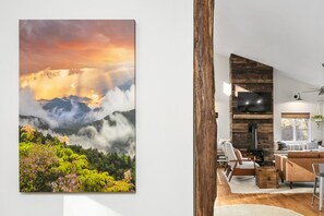 Ein Wohnzimmer mit Kamin, einer Couch und einem an einer Holzwand befestigten Fernseher.
