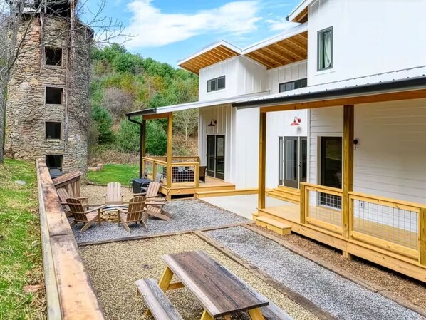 A modern building with a stone tower, outdoor seating, and a covered patio area.