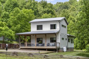 A two-story house with a porch, a small attached garage, and a yard with a fence. - Cozy Luxury Farmhouse, Minutes To Downtown & BRPW (Asheville)