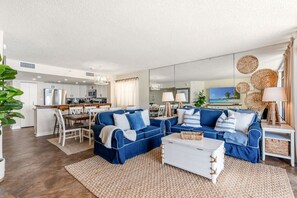 A modern living room with a sofa set, a coffee table, and a dining area with chairs and a table. - Oceanfront 4BR Condo | Stunning Views + Lazy River (North Myrtle Beach)