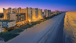 A beachfront hotel with multiple high-rise buildings, a sandy beach, and a clear sky. - Oceanfront 4BR Condo | Stunning Views + Lazy River (North Myrtle Beach)