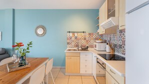A compact kitchen with a dining area, featuring a tiled backsplash, wooden cabinets, and a small refrigerator. - Vacation Home 'Vistamar-lovely Renovated With' with Wi-Fi (La Matanza de Acentejo)