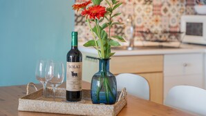 A bottle of wine, two glasses, and a vase with flowers on a table. - Vacation Home 'Vistamar-lovely Renovated With' with Wi-Fi (La Matanza de Acentejo)