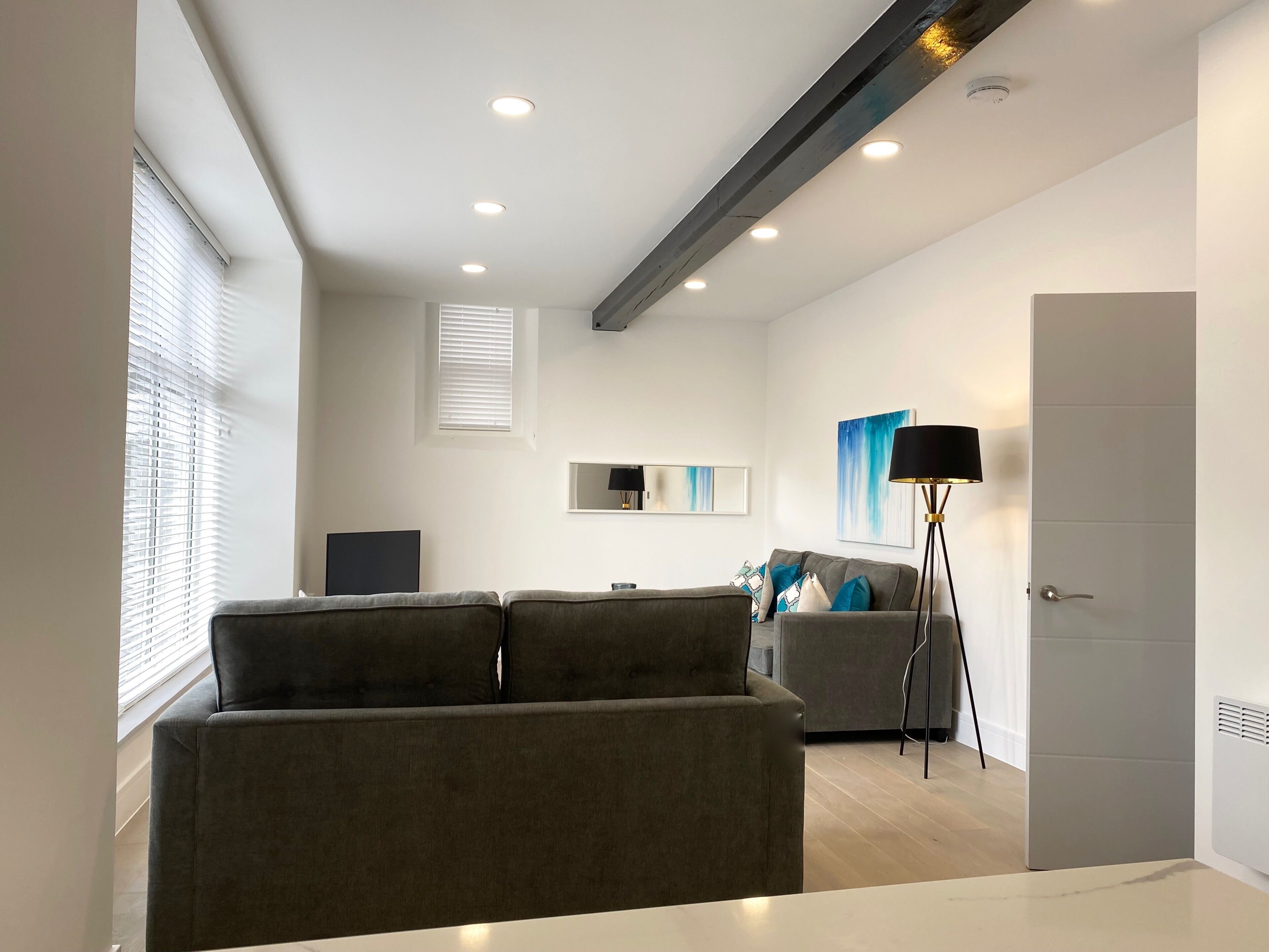 Un salon moderne avec un canapé gris, un lampadaire et un téléviseur à écran plat.