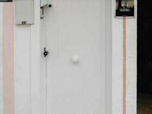 A white door with a keyhole and a round doorknob, a security camera, and a sign reading 'AIRÉN CENCIBEL' on the wall. - Airén Harbor's Light (La Vila Joiosa)