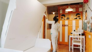 A room with a white sofa, a small table with chairs, a wall with a Santa Marta II sign, and a door with a number plate. - Cencibel Harbor's Light (La Vila Joiosa)