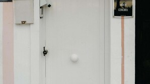 A white door with a keyhole and a round doorknob, a security camera, and a sign reading 'AIRÉN CENCIBEL' on the wall. - Cencibel Harbor's Light (La Vila Joiosa)