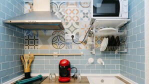 Una cocina con microondas, cafetera, lavamanos y un portalapices.