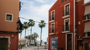 Una calle con edificios, palmeras y un patinete.