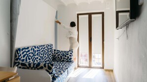 Una habitación con sofá, una puerta y televisor montado en la pared.