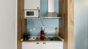 Una cocina compacta con microondas, estufa y cafetera.