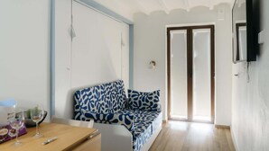 Habitación con sofá, una mesa con vasos y una barra de chocolate, televisión y puerta que da al exterior.