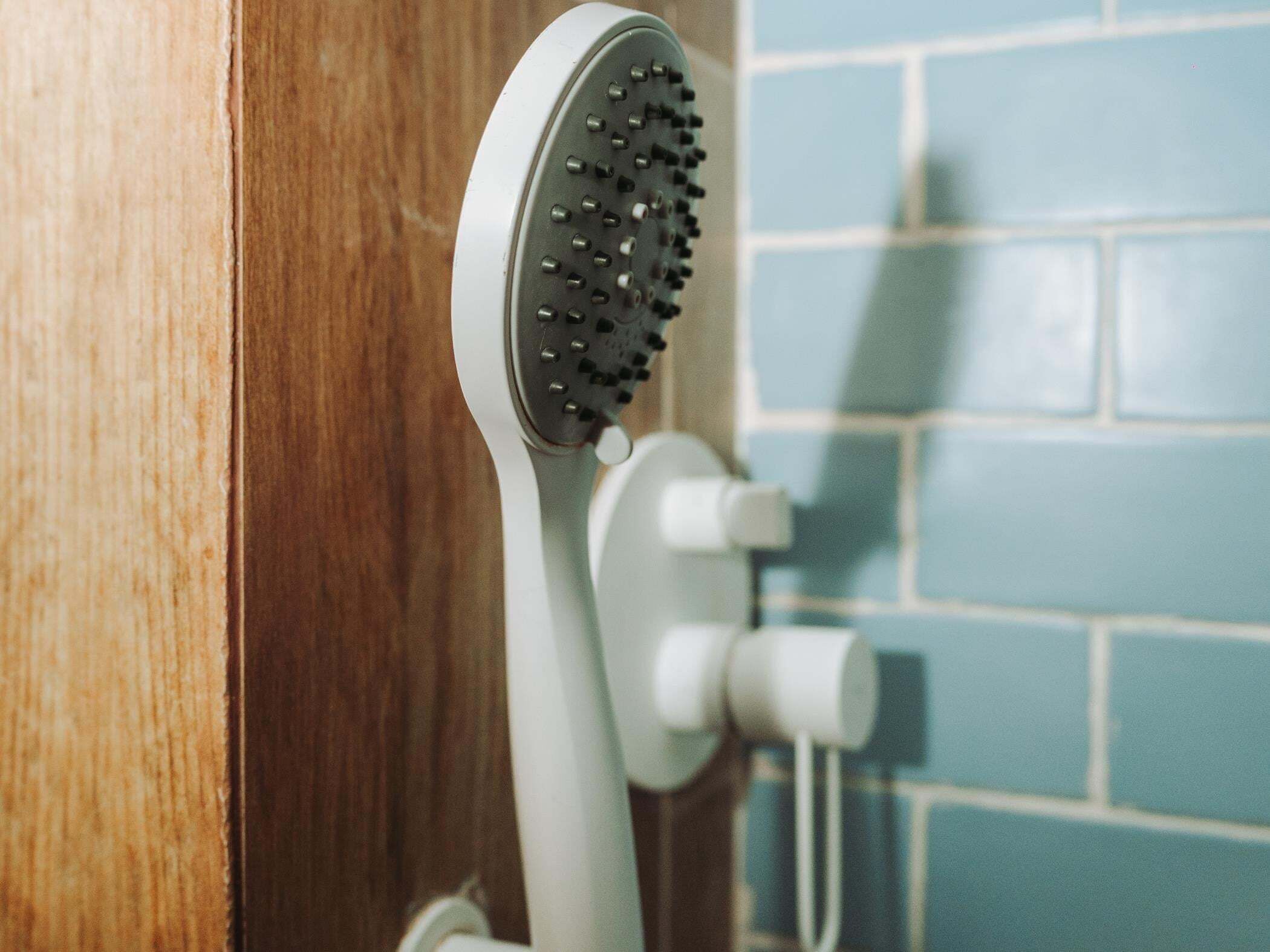 A showerhead mounted on a wall with a tiled backsplash.