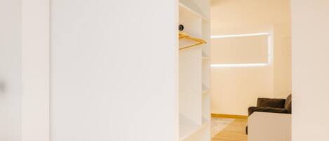 Un interior moderno con un armario blanco, suelo de madera y un sofá en una habitación luminosa.