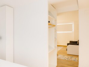 Un intérieur moderne avec une armoire blanche, un plancher en bois et un canapé dans une pièce bien éclairée.