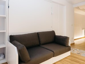 A modern living room with a brown sofa, white walls, and a wooden floor. - Pinot Noir Harbor's Light (La Vila Joiosa)