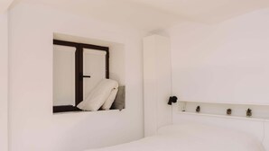 A minimalist bedroom with a bed, a window with a view, and a small shelf with decorative items. - Pinot Noir Harbor's Light (La Vila Joiosa)