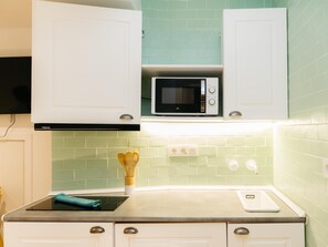 A kitchen with white cabinets, a microwave, and a countertop with a cutting board and utensils. - Pinot Noir Harbor's Light (La Vila Joiosa)