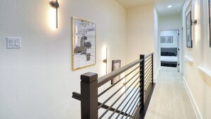 En hall med en lampa, en inramad affisch och en säng i bakgrunden.