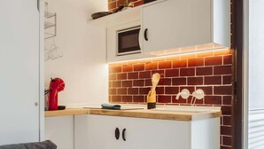 Une cuisine avec des armoires blanches, un four à micro-ondes, un dosseret en briques et un plan de travail en bois.