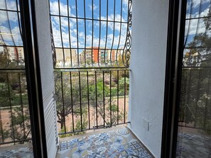 A balcony with a metal railing, a tiled floor, and a view of buildings and greenery. - Moscatel Harbor's Light (La Vila Joiosa)