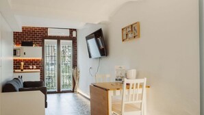 Un espace de vie compact comprenant une cuisine, un coin repas et un téléviseur fixé au mur.