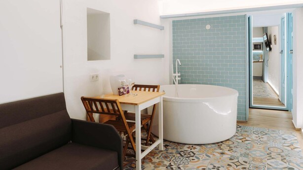 Un baño moderno con una bañera grande, una mesa de madera con sillas, y un piso con diseño.