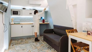 Una cocina compacta con microondas, cafetera y televisor de pantalla plana montado en la pared.